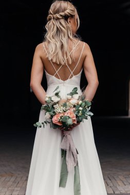 konsept ve şık gelin arkasında güzel bir düğün buketi tutuyor.