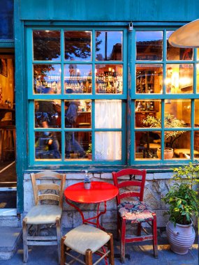 İoannina şehrinde akşam vakti kafenin penceresinin kapısı masa sandalyeleri şişeler.
