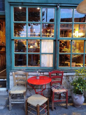 İoannina şehrinde akşam vakti kafenin penceresinin kapısı masa sandalyeleri şişeler.