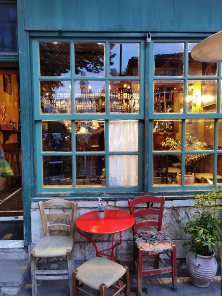 İoannina şehrinde akşam vakti kafenin penceresinin kapısı masa sandalyeleri şişeler.