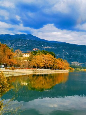 İoannina şehrinde sonbahar. Yunan. Ağaçlarda sarı yapraklar ve göl kenarında bulutlar.