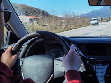 Şoför şehirde araba kullanırken arka koltuktan araba görüntüsü.