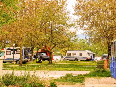 bahar tatilinde göl kenarındaki çiçeklerin arasında karavan arabaları ağaçların arasında