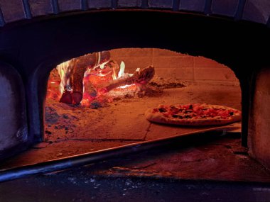 Pizzalar fırında sıcak, odunlar ve şöminede taze pişmiş yemekler.
