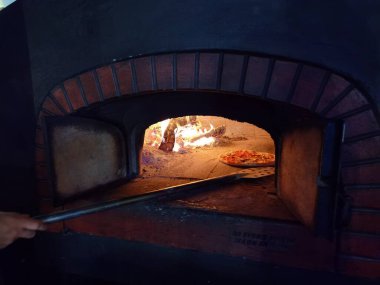 Pizzalar fırında sıcak, odunlar ve şöminede taze pişmiş yemekler.
