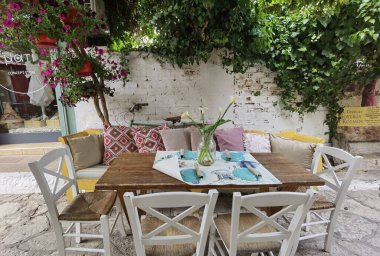 Greece Preveza şehrinin sokaklarındaki saksılarda masalarda kırmızı güller.