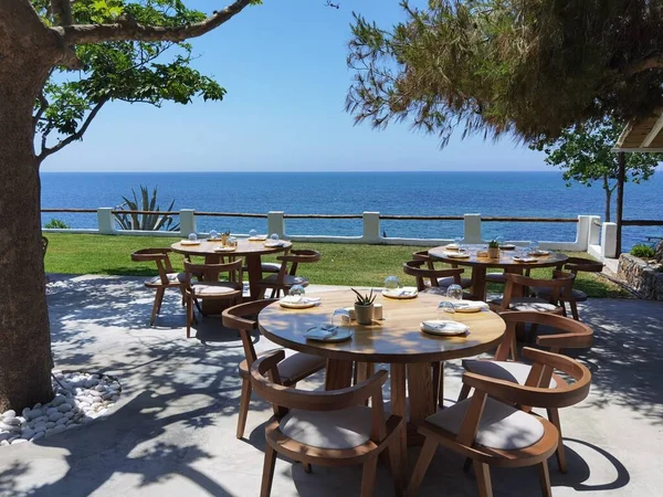 緑の木々の影の下の海のそばのレストランのテーブルとプレートギリシャ語プレヴェザの完成 — ストック写真