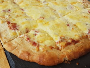 Siyah ahşap masa yemeği arka planında peynirli pizza.