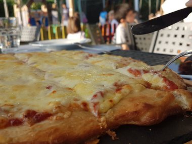 Siyah ahşap masa yemeği arka planında peynirli pizza.