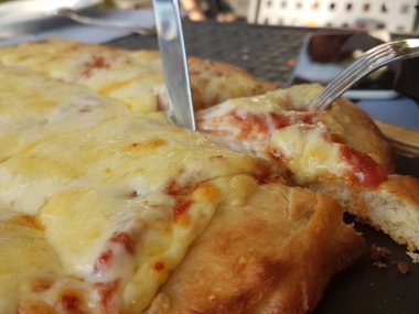 Siyah ahşap masa yemeği arka planında peynirli pizza.