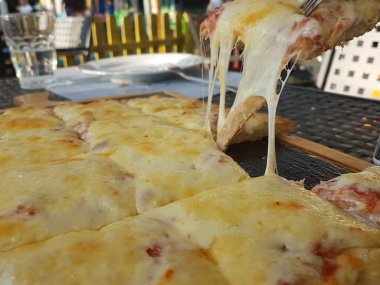 Siyah ahşap masa yemeği arka planında peynirli pizza.
