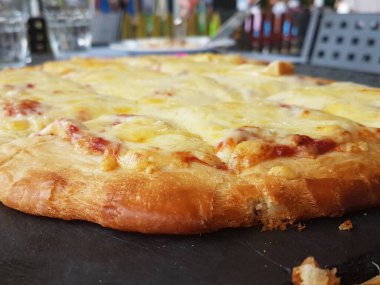 Siyah ahşap masa yemeği arka planında peynirli pizza.