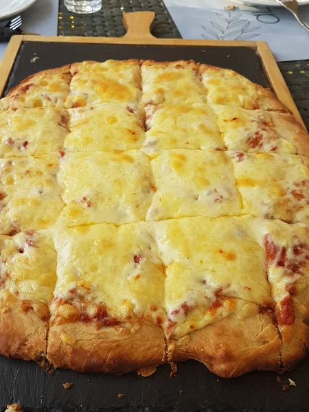 Siyah ahşap masa yemeği arka planında peynirli pizza.