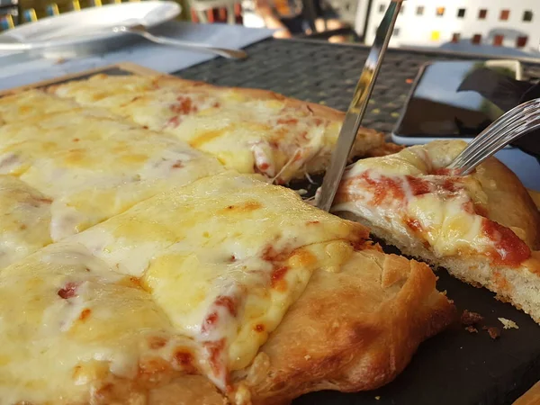 Siyah ahşap masa yemeği arka planında peynirli pizza.