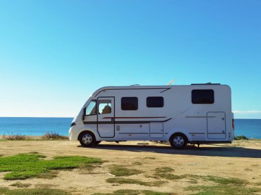 Sabah güneş doğmadan önce deniz kenarında park etmiş bir karavan.