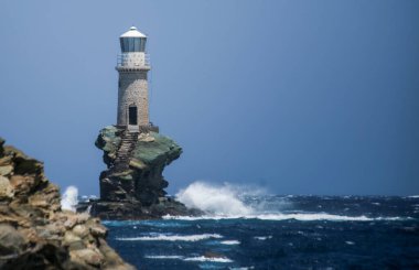 lighthouse in andros island greece in day light and sea waves in a windy day
