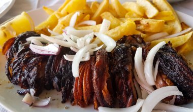 meat called kokoretsi in a plate with potatoes and onion greek kitchen food