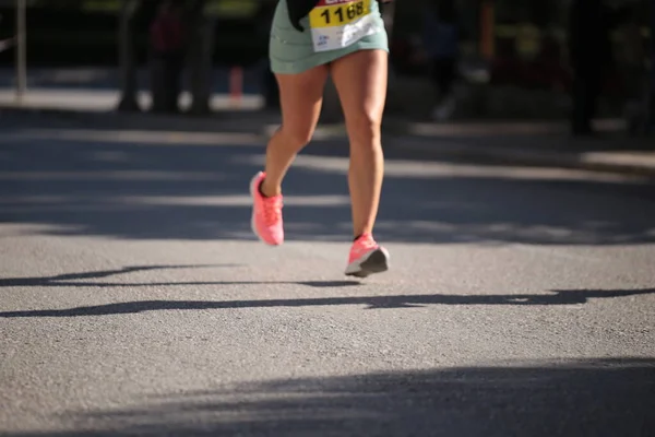 在城市赛跑鞋的柏油路上跑着的脚步声使跑着的女高音腿抽筋 — 图库照片