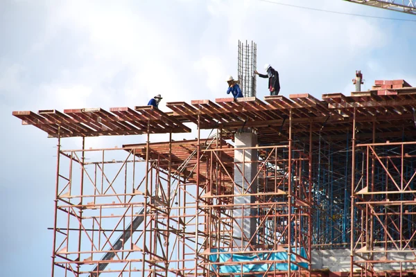 Crane and workers at construction site against blue sky. Thailand — Stock Photo, Image