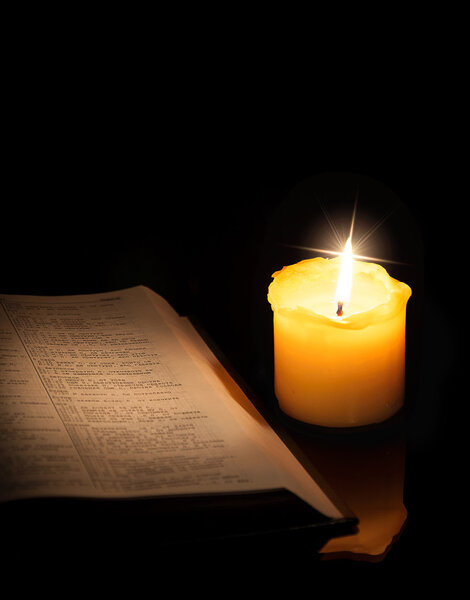 Open book and burning candle