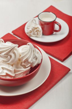 Beyaz meringues ve kırmızı bir bardak süt ile.