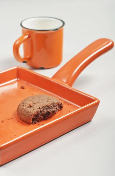 Broken biscuit and orange cup — Stock Photo, Image