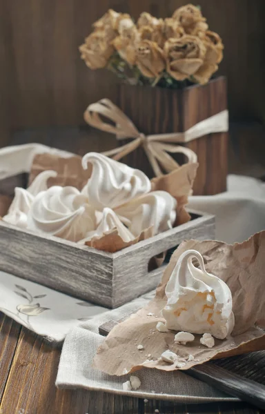 Meringues in wooden box and dry roses