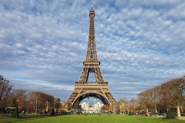 Paris'te Eyfel Kulesi ile yeşil çimen, mavi gökyüzü ve beyaz bulutlar