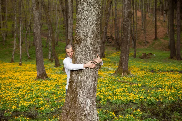 A happy man hugging a tree in forest — Stock Photo, Image