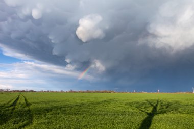 mammatus bulutlar ve yol ve yeşil bir arazi üzerinde bir gökkuşağı