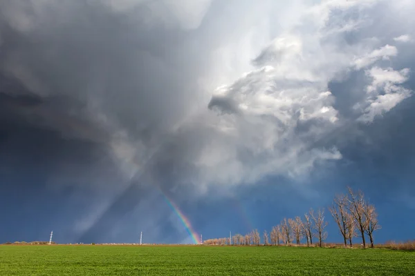 Gewitterwolken mit Regenbogen und Straße mit Bäumen — Stockfoto