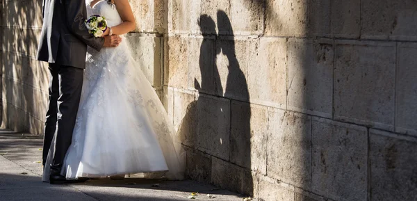 Bruid en bruidegom kissin in de buurt van muur met schaduw — Stockfoto