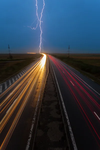 Thunderstorm and lightnings in night over highway with cars movi