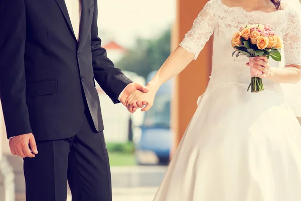 Свадебная пара, держащаяся за руки с цветами — стоковое фото