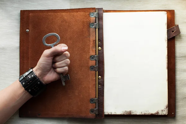 Holding an old key over a book — Stock Photo, Image