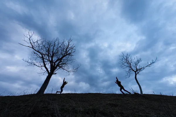 Happy children running between trees over the clouds — Stock Photo, Image