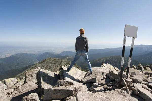 Giovane uomo in piedi sul bordo della scogliera e guardando in una vasta valle — Foto Stock