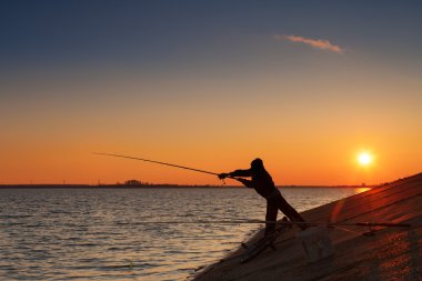 balıkçı balıklar nehir kıyısında günbatımı karşı silüeti