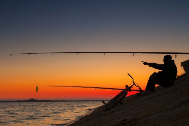 Ona yakın bisiklet ile göl kenarında bekleyen balıkçı