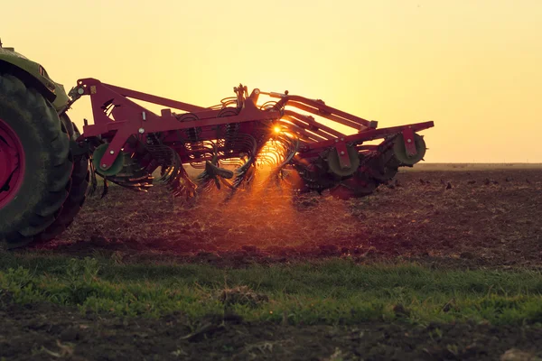 Tractor al atardecer haciendo agricultura — Foto de Stock