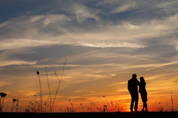 Silueta de mujer embarazada y un hombre al atardecer — Foto de Stock