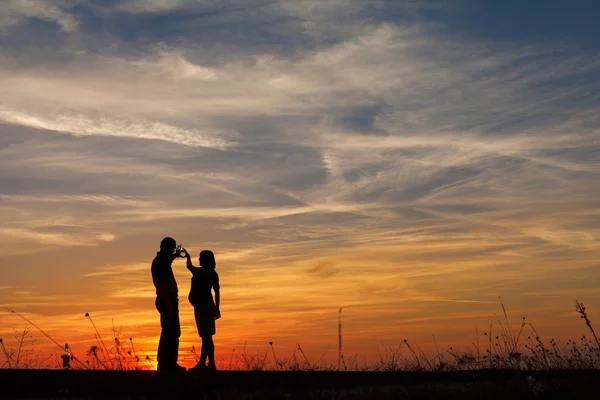 Hamile kadın ve bir adamın günbatımında siluet — Stok fotoğraf