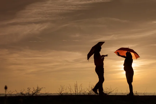 Silhueta de mulher grávida e um homem no pôr do sol — Fotografia de Stock