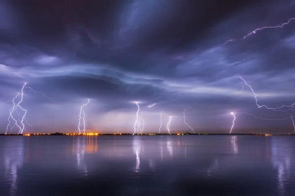 Tormenta y relámpagos en la noche sobre un lago con reflejos — Foto de Stock