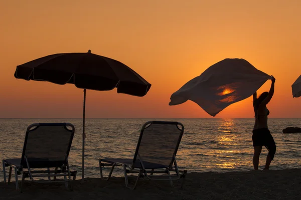 Sunset bulvarında bir kumsalda yürüyen genç bir kadın — Stok fotoğraf