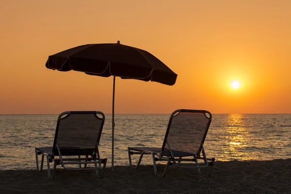 美丽的海滩与甲板椅子和日落时太阳伞 — 图库照片