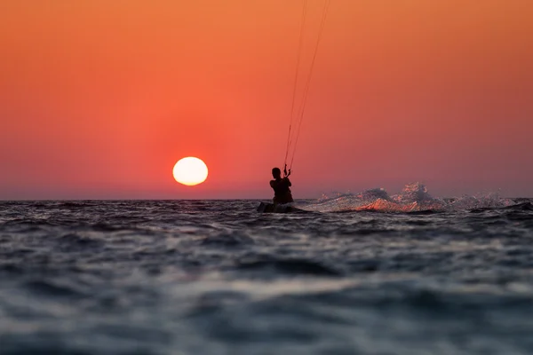 Silhouette d'un kitesurfer naviguant au coucher du soleil — Photo