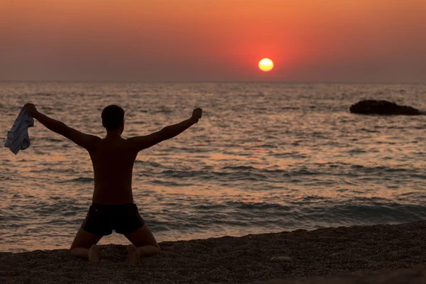 Homme les mains en l'air à l'aube sur la plage — Photo