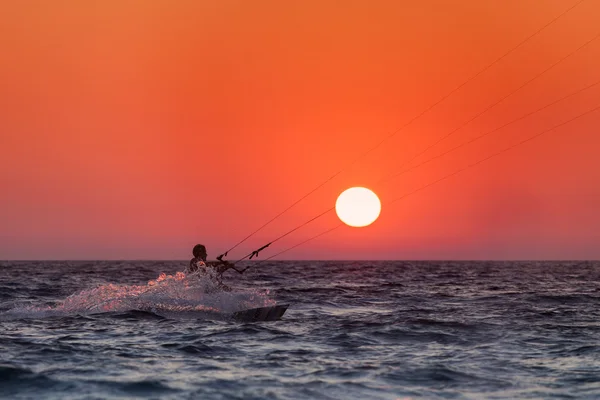 Silhuetten av en kitesurfare segling vid solnedgången — Stockfoto