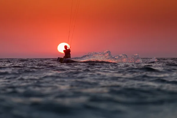 Silhouette d'un kitesurfer naviguant au coucher du soleil sur le soleil — Photo